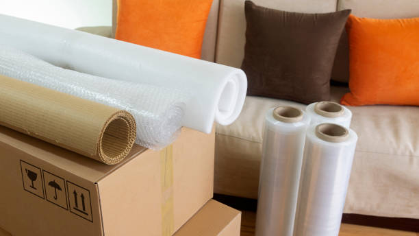 Mover sealing a cardboard box with tape during a house move in Al Nuaimiya Ajman